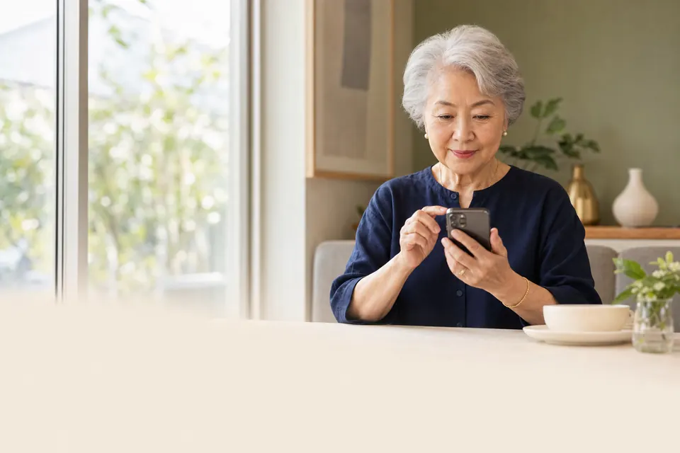 An older woman comfortably reviewing her phone at home